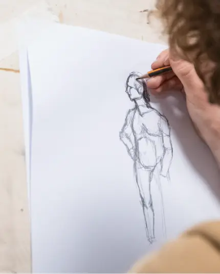 Primo piano di una mano che disegna con precisione una figura umana stilizzata a matita su un foglio bianco.