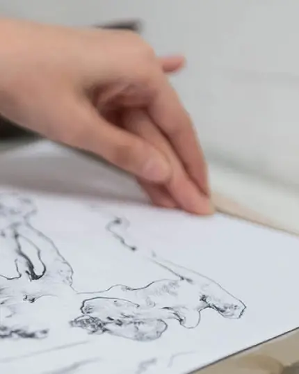 Dettaglio ravvicinato di una mano che esegue una tecnica di incisione o disegno artistico lineare su carta.